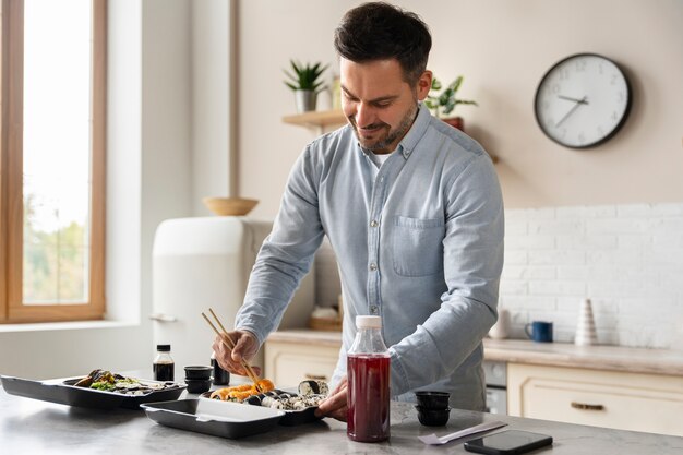 Uomo del colpo medio che mangia sushi