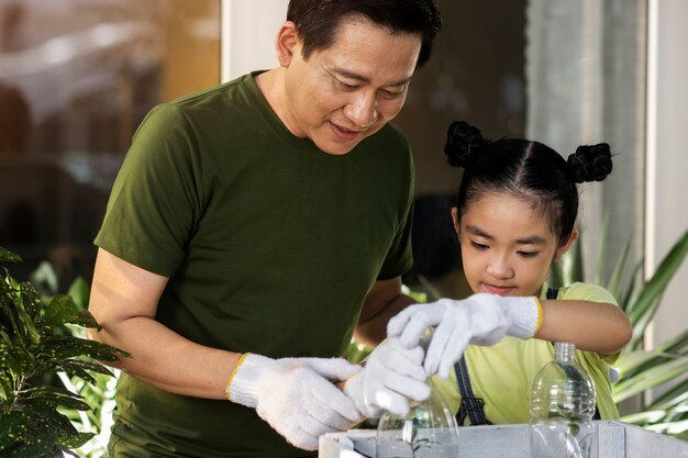 Medium shot man and girl reusing plastic bottles