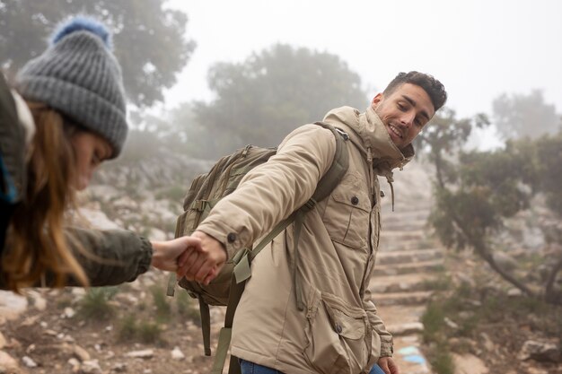 Medium shot man helping woman to climb