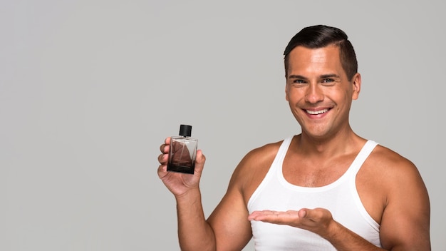 Free photo medium shot man holding cologne