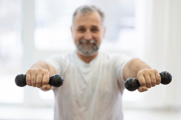 Free photo medium shot man holding dumbbells