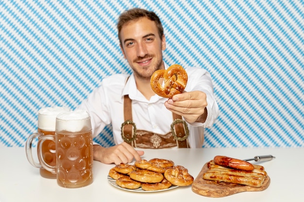 Medium shot of man holding german pretzel