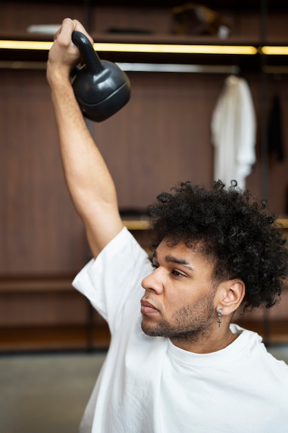 Medium shot man holding kettlebell up