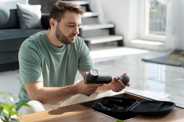 Medium shot man holding massage gun