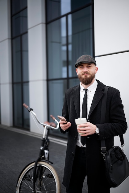 Medium shot man holding phone and coffee