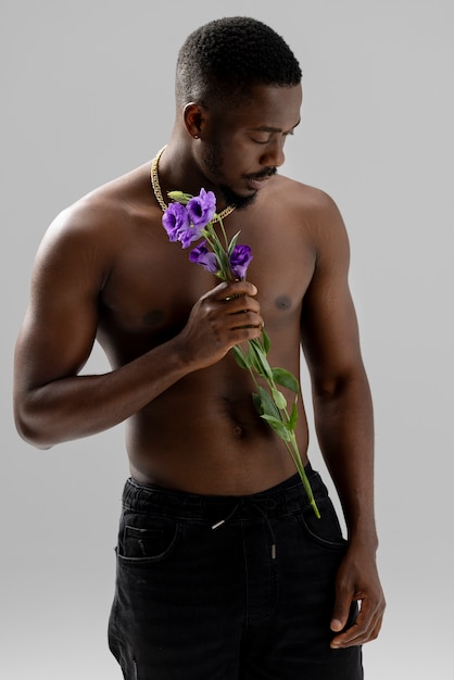 Бесплатное фото Мужчина среднего роста держит фиолетовый цветок