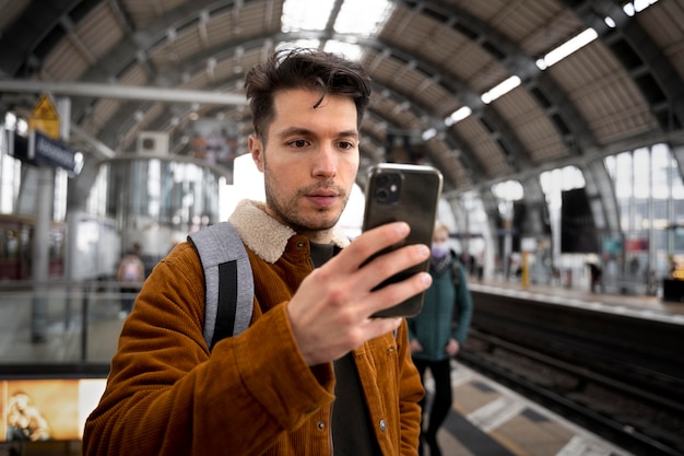 Foto gratuita uomo con colpo medio che tiene smartphone