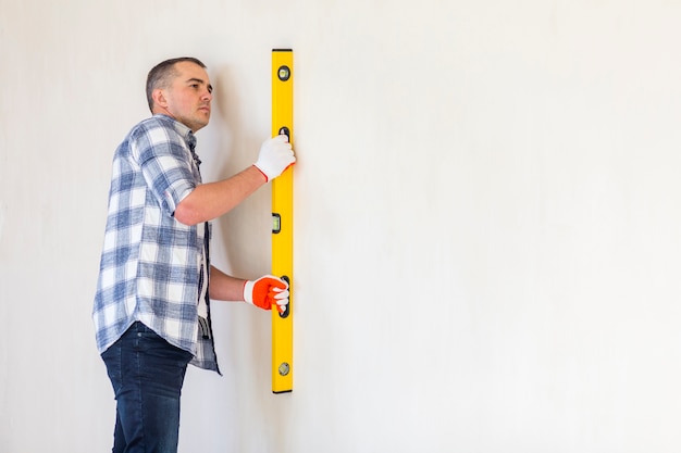 Free photo medium shot of man holding spirit level with copy space