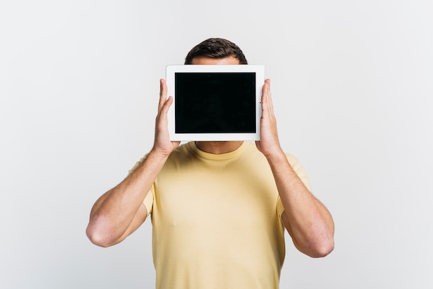 Free photo medium shot man holding a tablet in front of his face