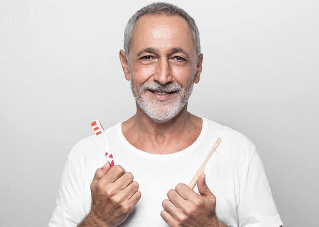 Medium shot man holding toothbrushes