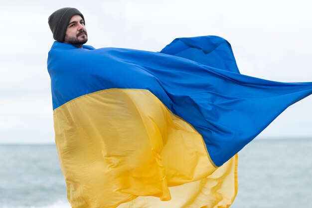 Мужчина среднего роста с украинским флагом на улице