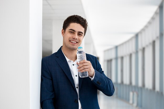 Мужчина среднего роста держит бутылку с водой