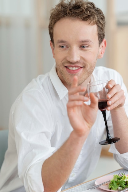 Uomo del colpo medio che tiene il bicchiere di vino