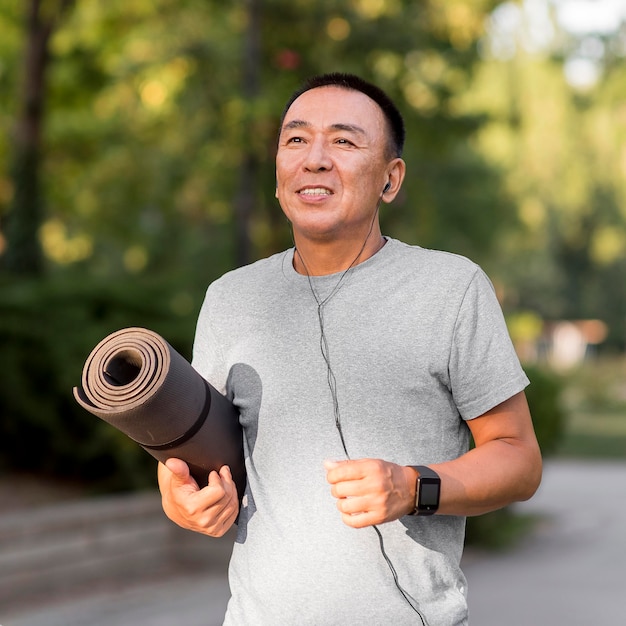 Medium shot man holding yoga mat