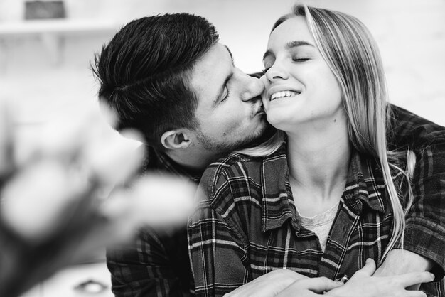 Средний снимок мужчина целует женщину в оттенки серого в щеку