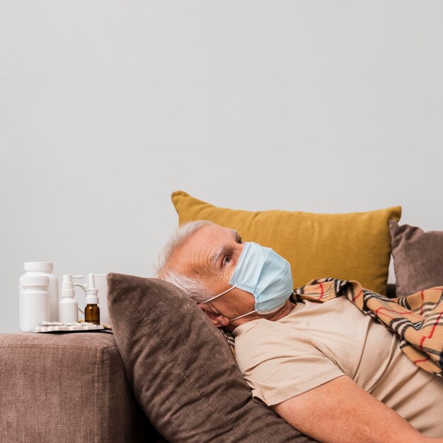 Medium shot man laying on couch with mask