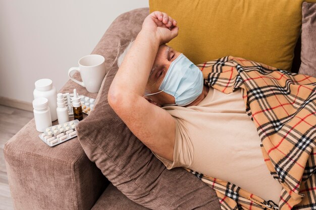 Medium shot man laying on couch with mask