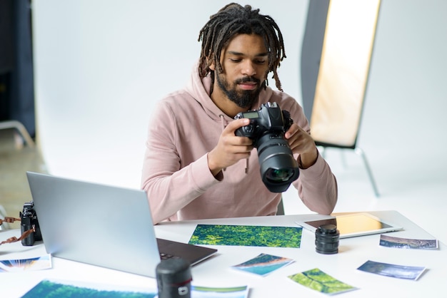 A photographer editing photos on a laptop, surrounded by cameras, lenses, and a globe representing global reach.