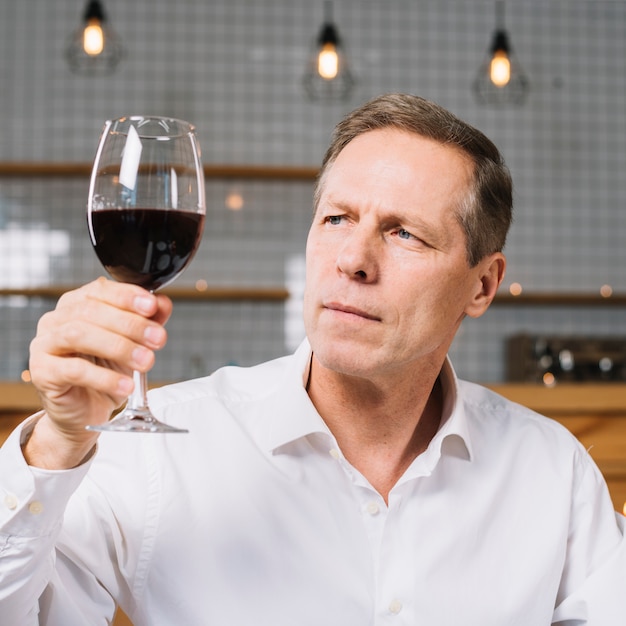 Free photo medium shot of man looking at wine glass