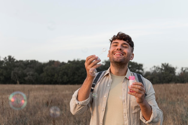 Medium shot man making soap balloons