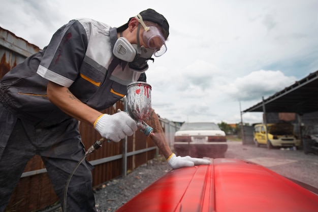 Foto gratuita portiera della macchina della pittura dell'uomo del tiro medio