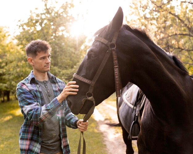 自然の中で馬をかわいがるミディアムショットの男