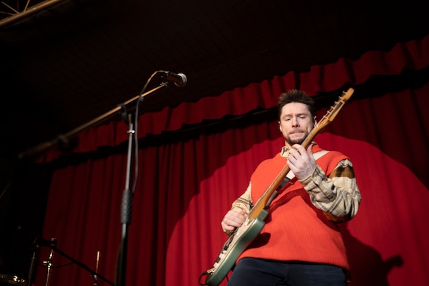 Foto gratuita uomo di tiro medio che suona la chitarra sul palco