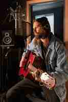 Free photo medium shot man playing the guitar in studio