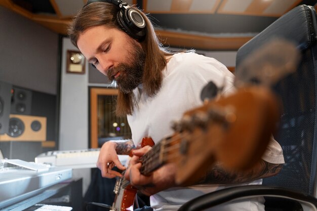 Medium shot man playing the guitar in studio
