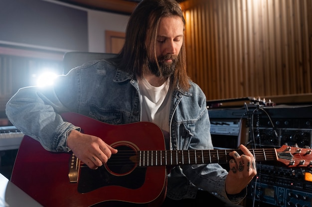 Medium shot man playing the guitar in studio