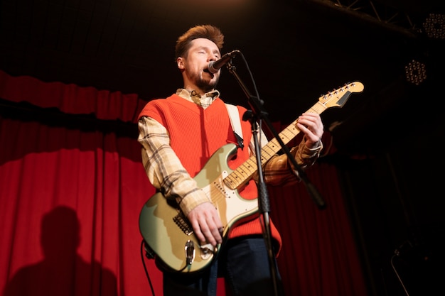 Uomo del tiro medio che suona la chitarra