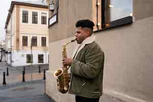 Free photo medium shot man playing saxophone