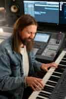 Бесплатное фото Мужчина среднего роста играет на пианино в студии