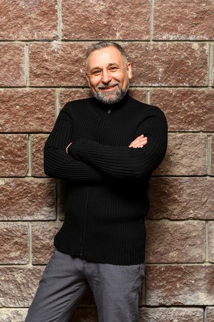 Medium shot man posing next to brick wall