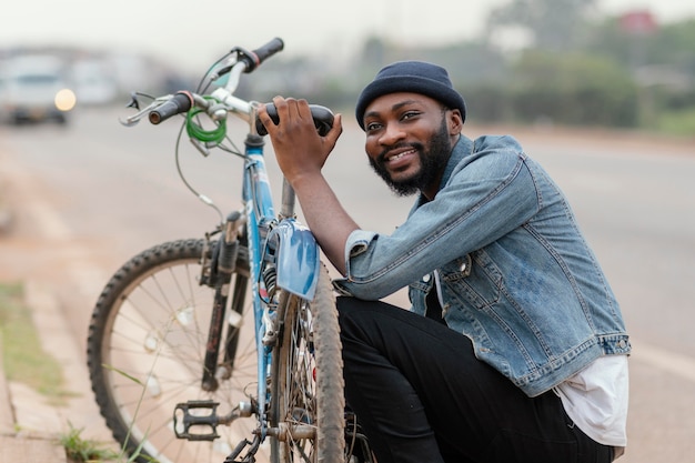 Medium shot man posing near bicycle