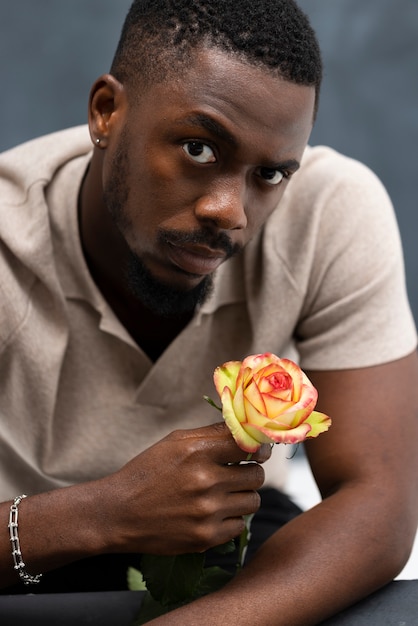 Medium shot man posing with beautiful flower