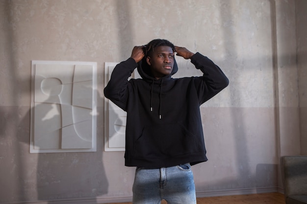 Medium shot man posing with hoodie indoors