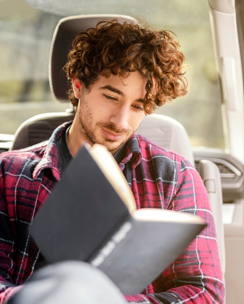 Uomo del colpo medio che legge in macchina