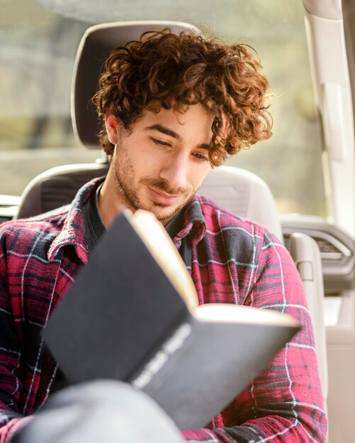 Мужчина среднего кадра читает в машине