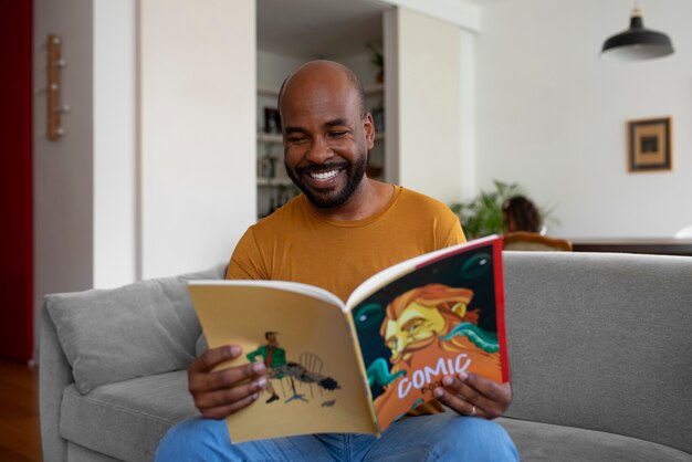 Medium shot man reading comics at home