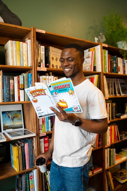 Foto gratuita uomo del colpo medio che legge i fumetti alla biblioteca