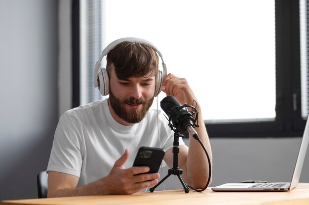 Medium shot man recording podcast inside