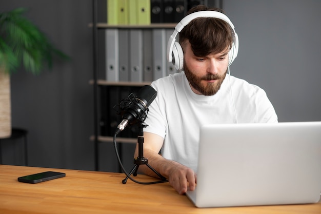 Podcast di registrazione di uomo di tiro medio con il laptop