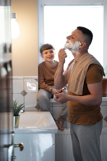 Uomo del tiro medio che si rade allo specchio