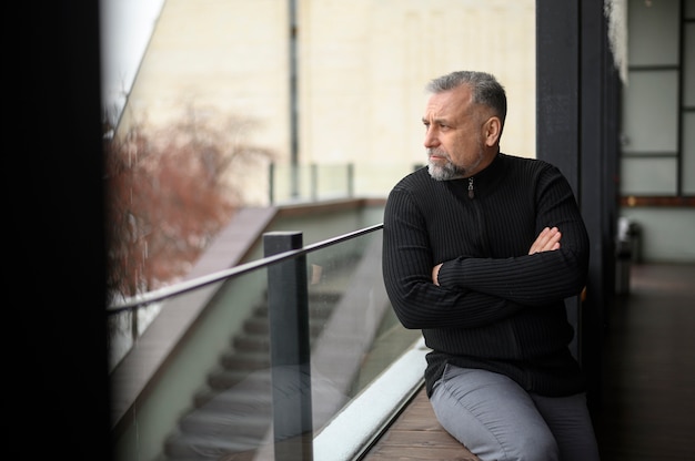 Free photo medium shot man sitting on a sill