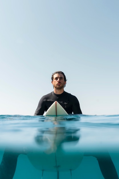 Medium shot man sitting on surfboard