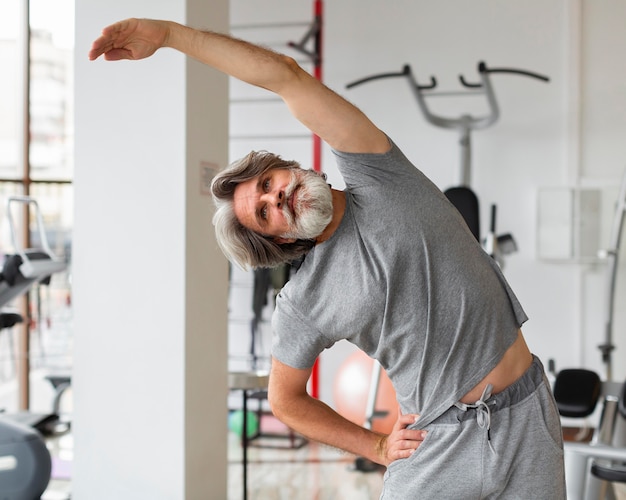 Medium shot man stretching at gym