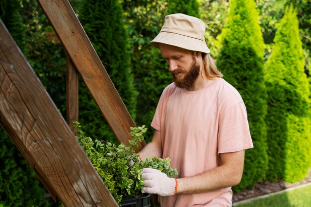 屋外で植物の世話をするミディアムショットの男