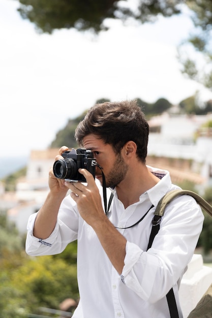 Средний снимок человека, делающего фотографии с камерой