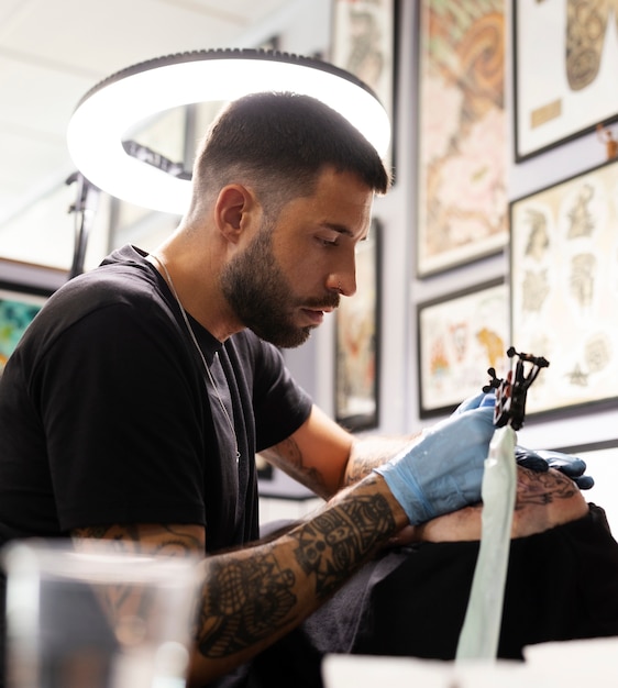 Free photo medium shot man tattooing customer